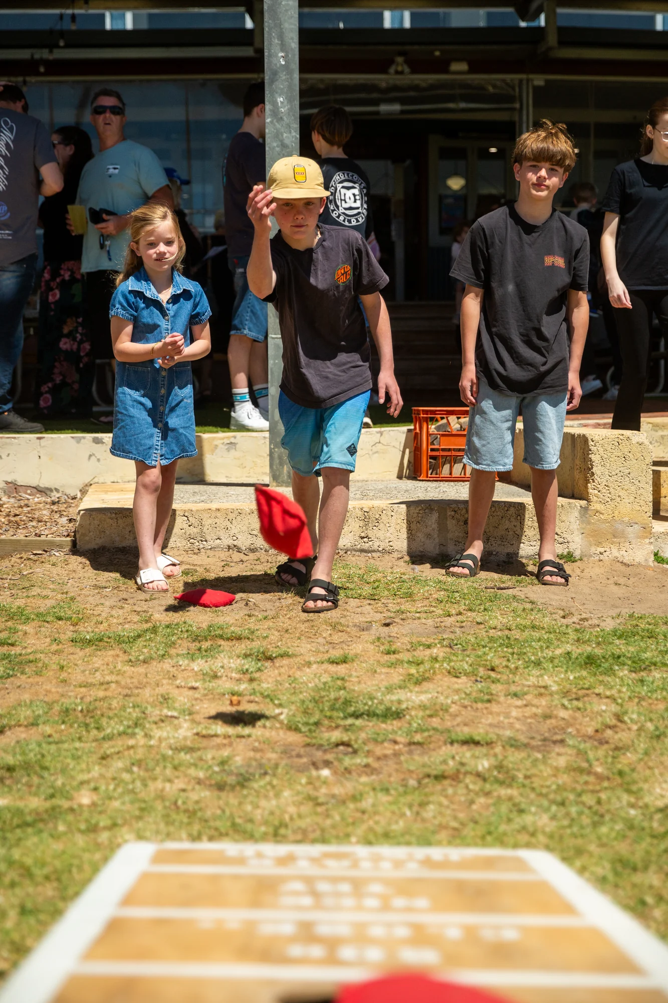 Children playing cornhole, with the game board in the foreground.
