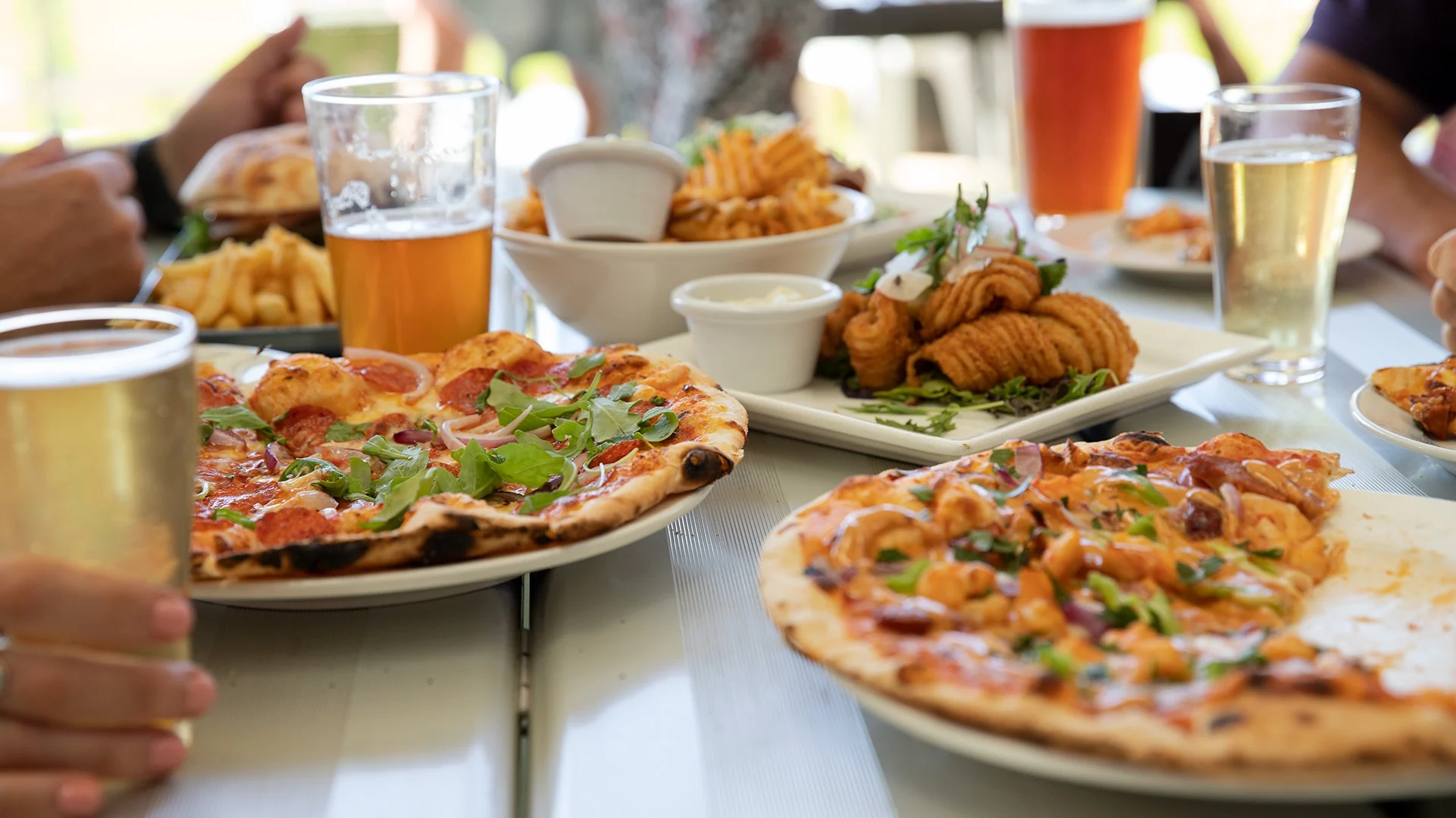 A table full of wood-fired pizzas, dishes and drinks at Old Coast Road Brewery