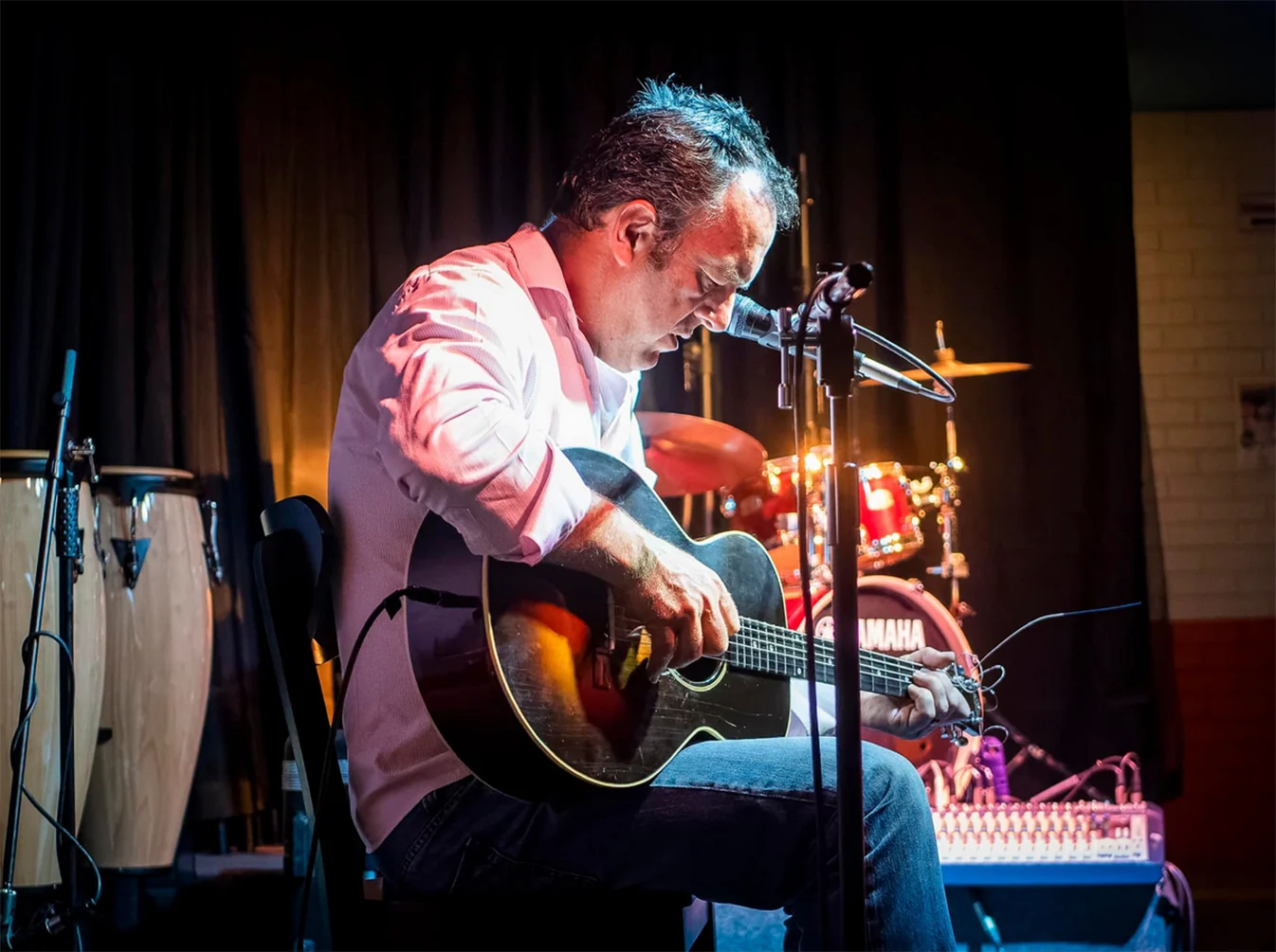 A musician singing and playing an acoustic guitar