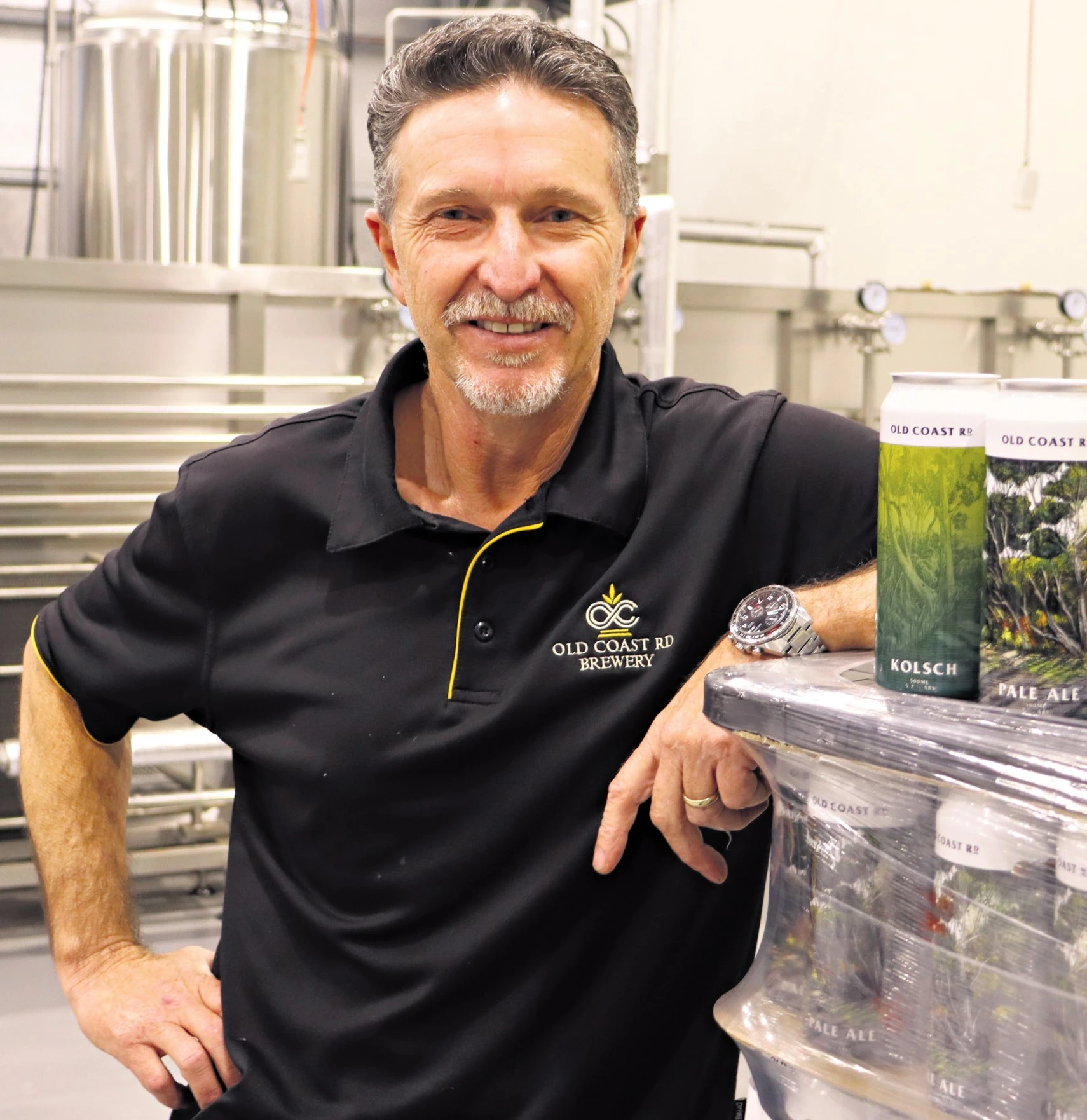 Andrew Harris in the Old Coast Road brewhouse with cans of OCRB beer in October 2024