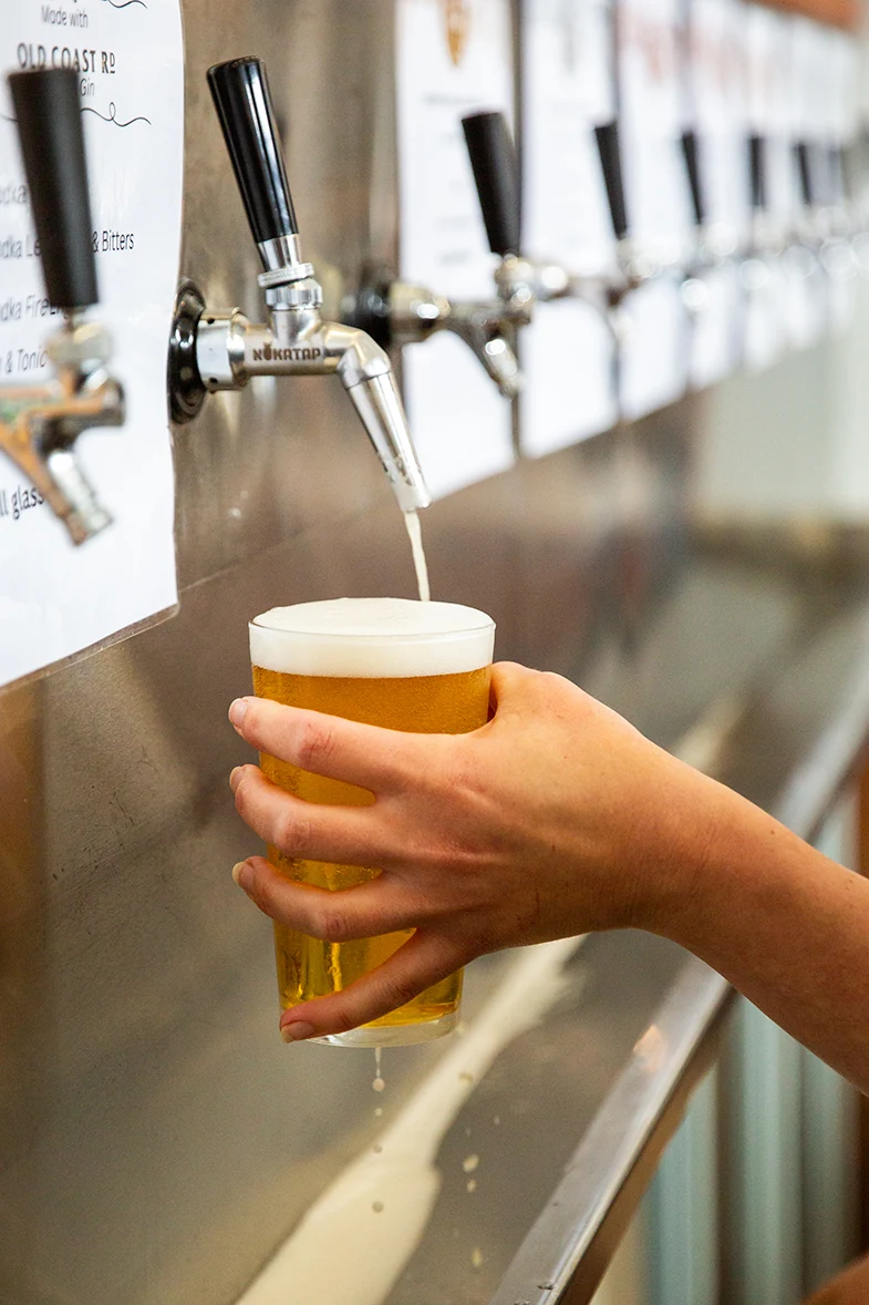 A glass of beer being poured from an Old Coast Road tap