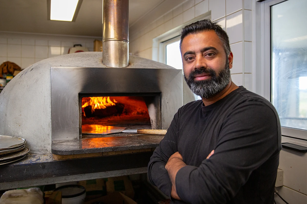 An Old Coast Road team member tending the woodfired pizza oven