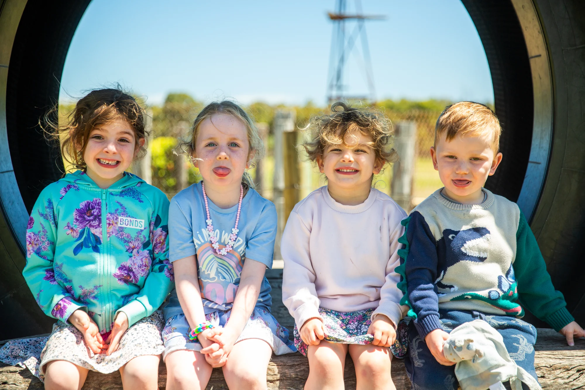 Four children smiling together in the giant tyre at Old Coast Road mini golf