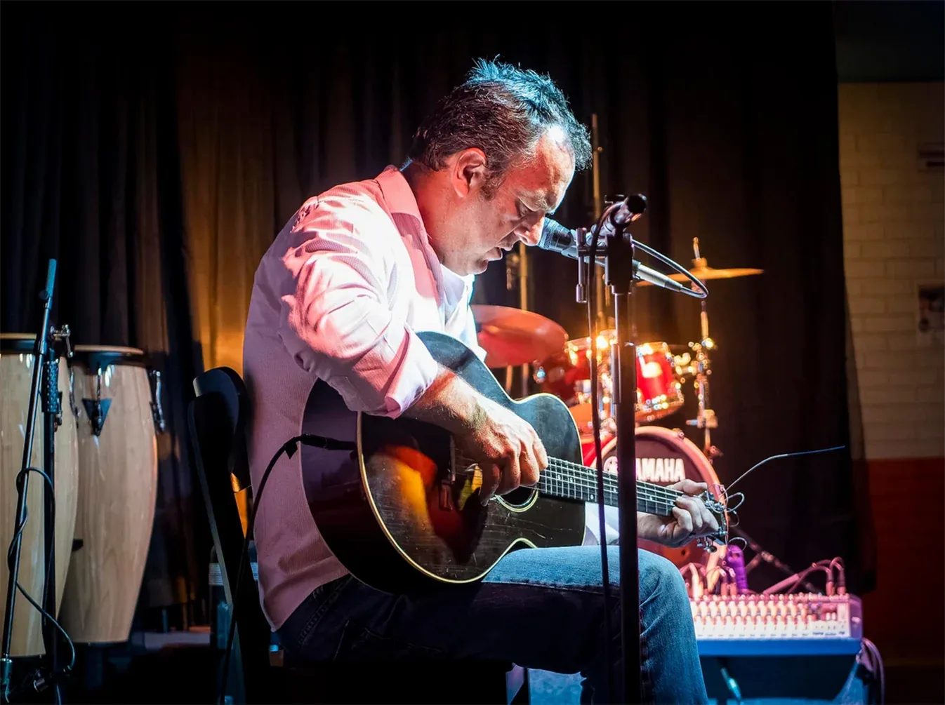 A musician singing and playing an acoustic guitar